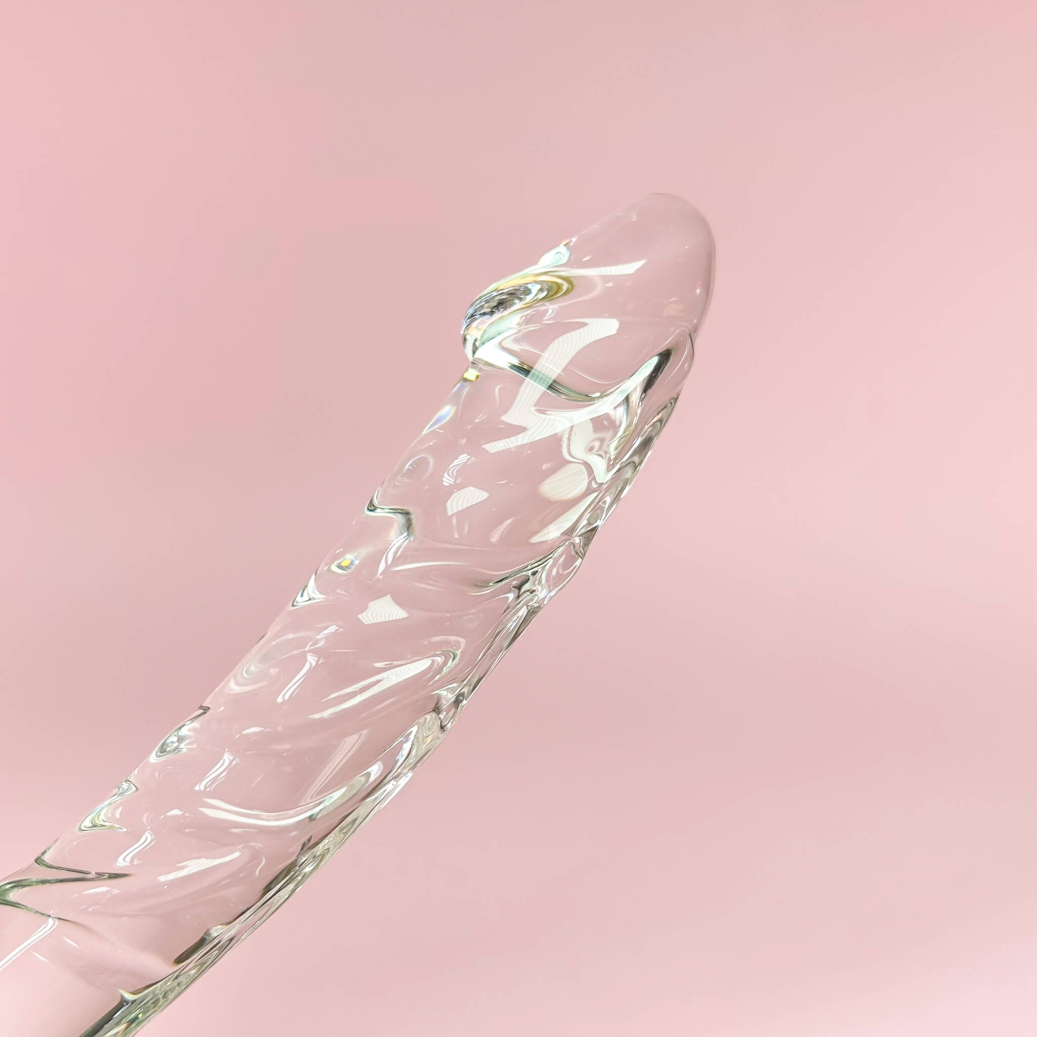 Clear glass dildo on a pink background
