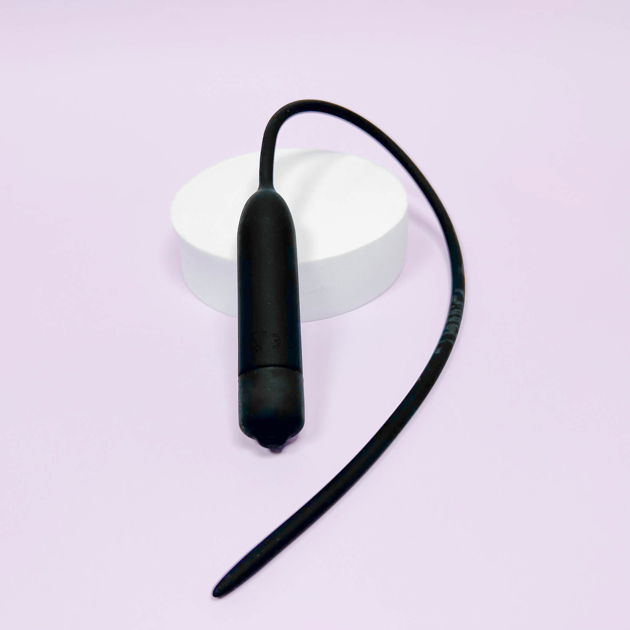 Extra Long Silicone Urethral Vibrator Plug on a light purple background