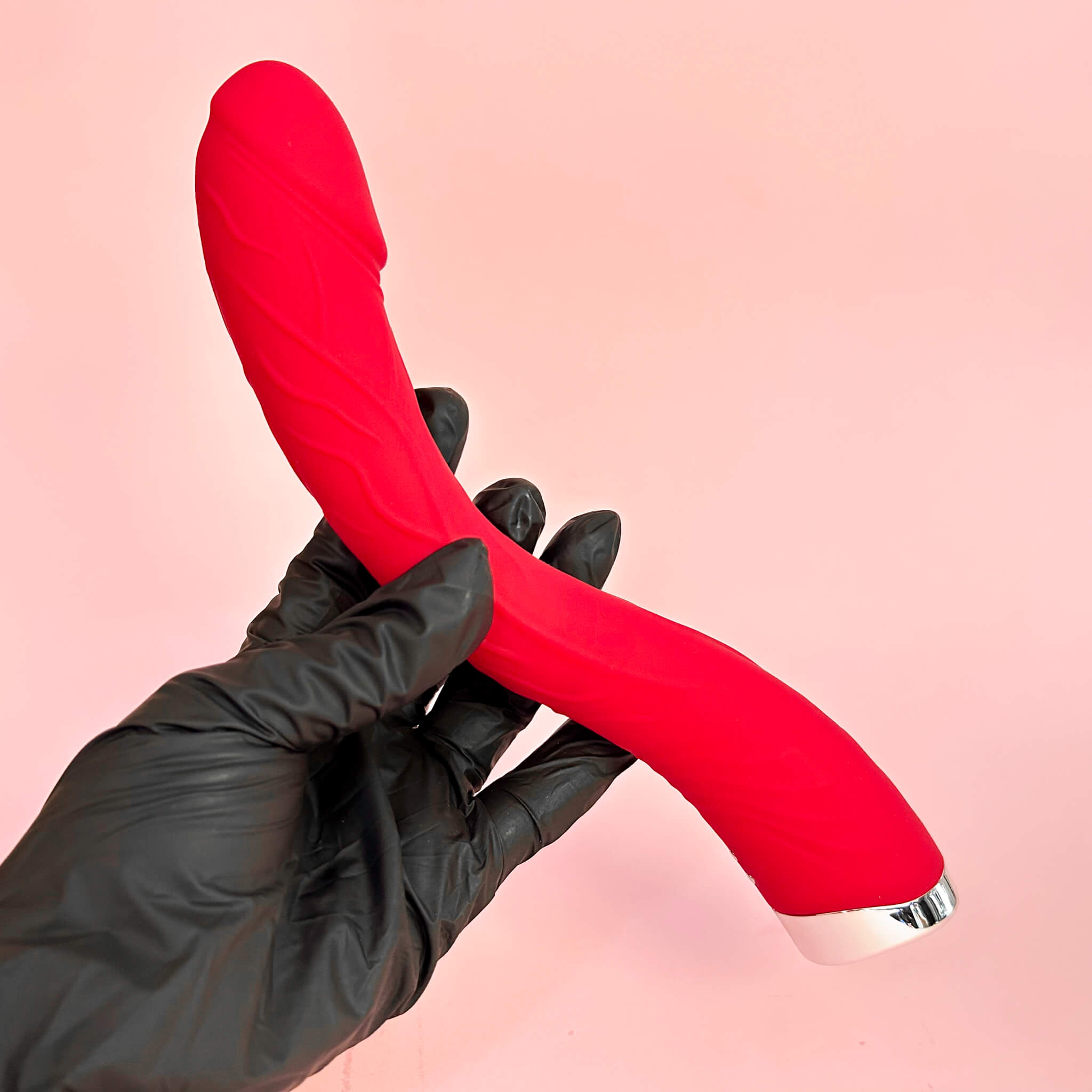 Flexicurve Realistic G-Spot Vibrator by a gloved hand against a pink background