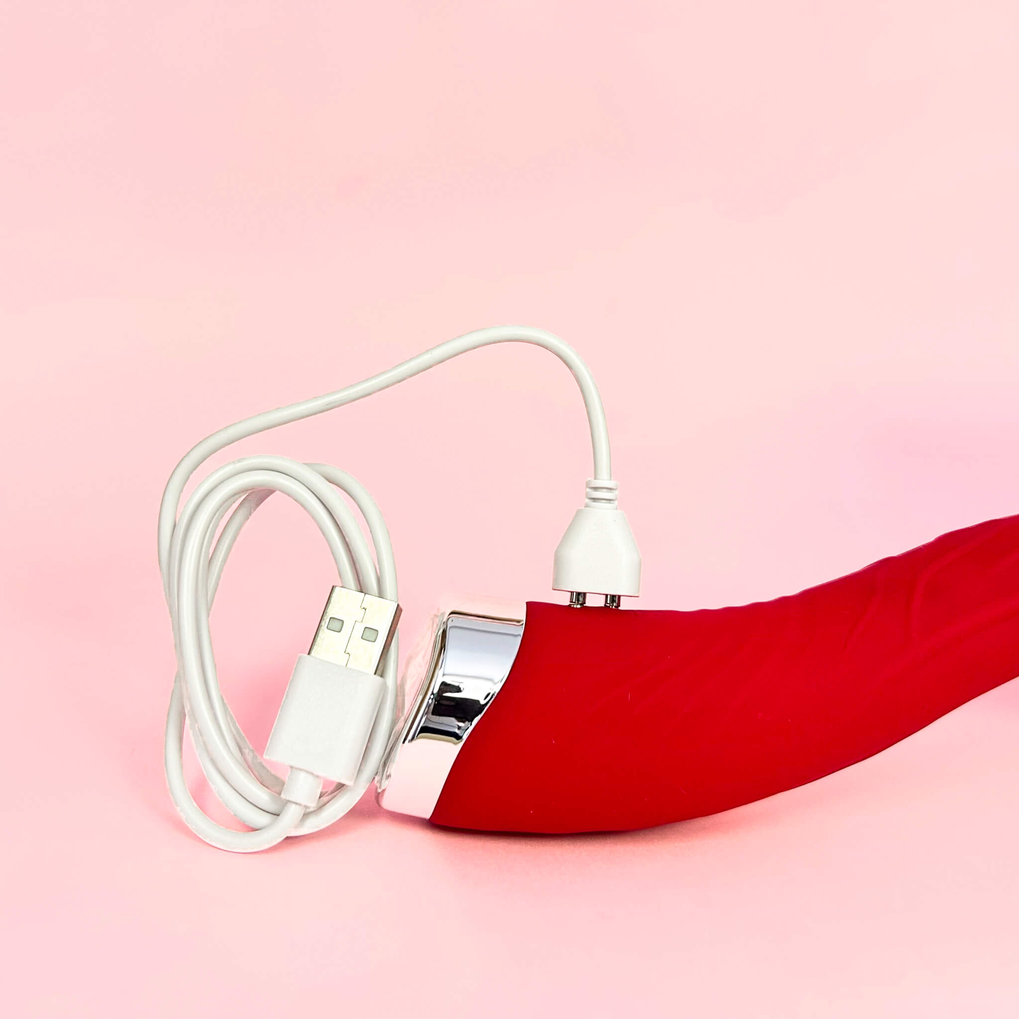 White USB cable with a G-Spot Dildo Vibrator on a pink background