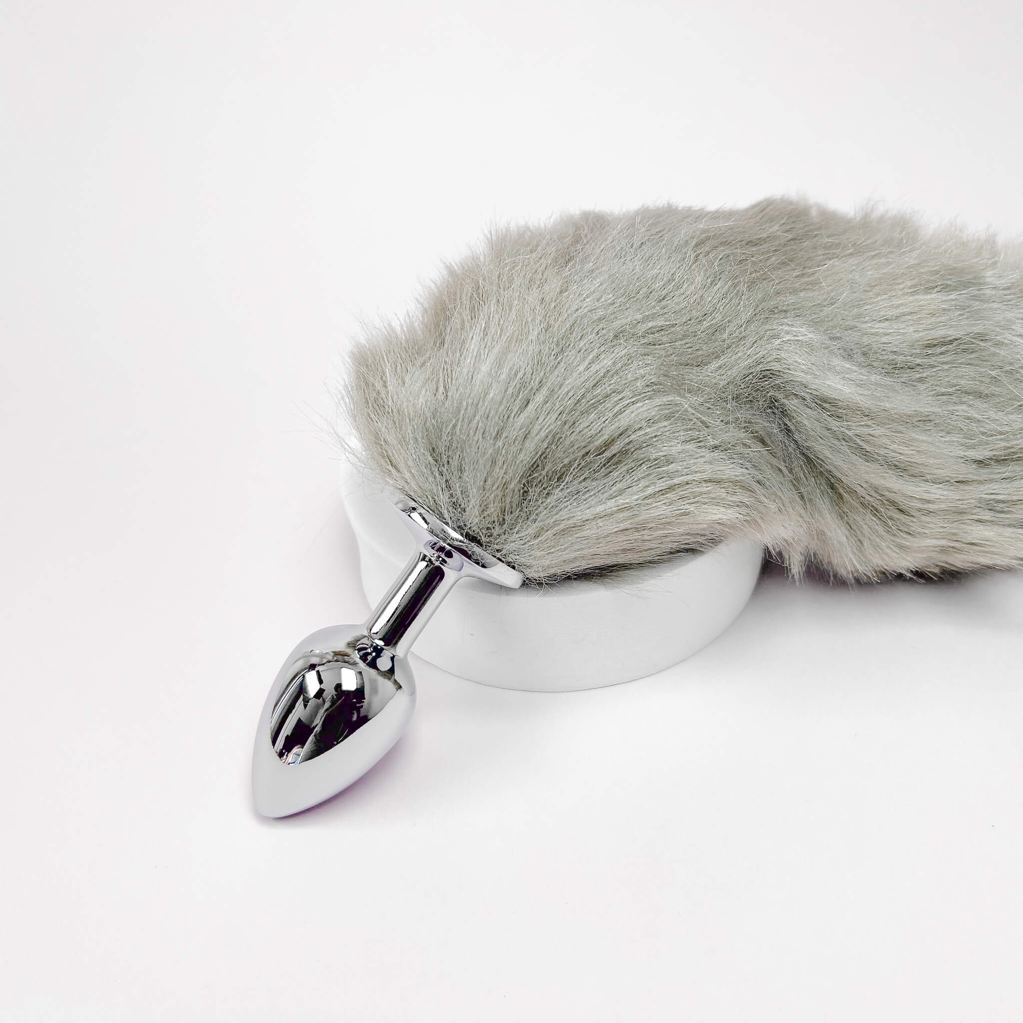 Metallic anal plug with gray fur cover on a white background