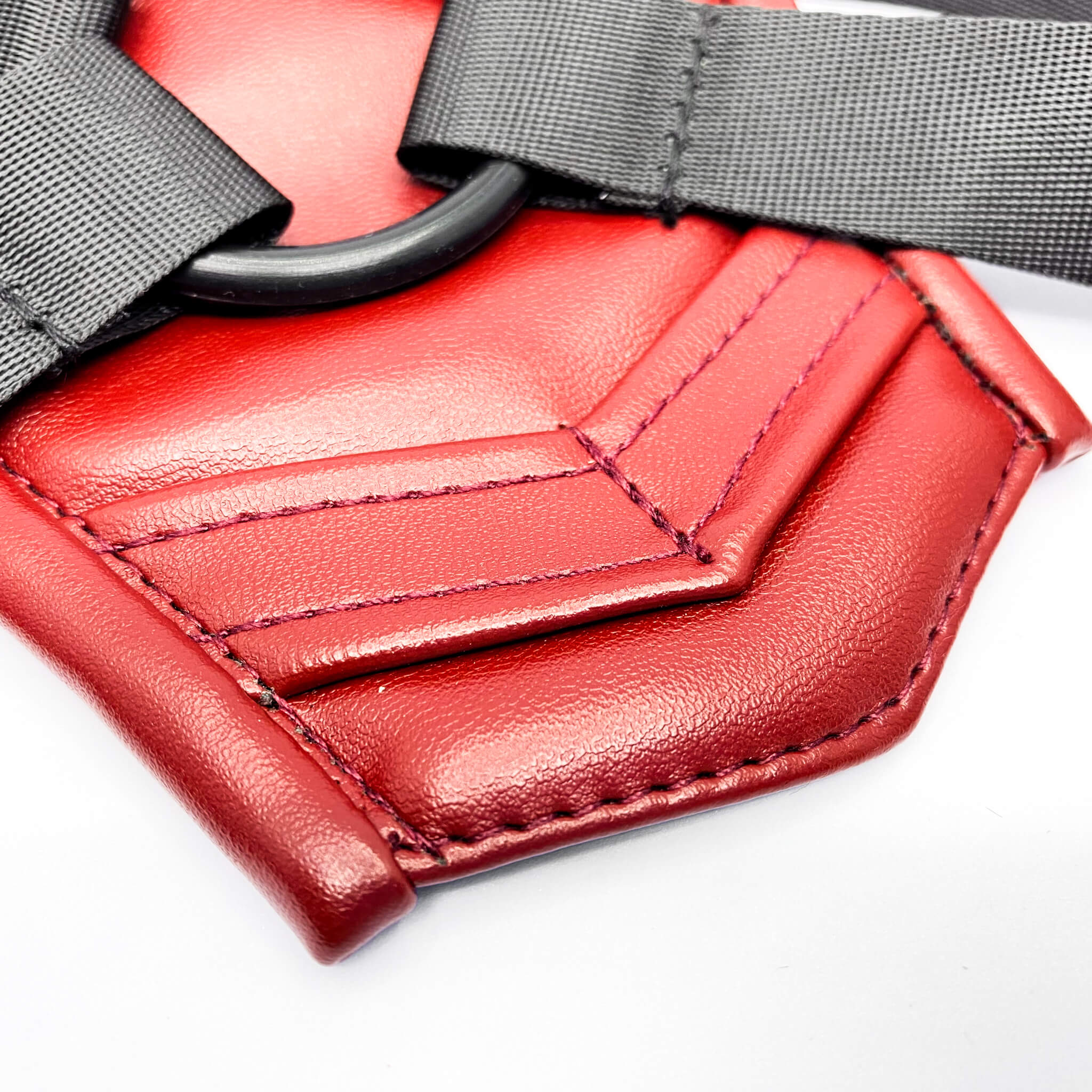 Close-up of a red leather strap with gray buckle on a white background