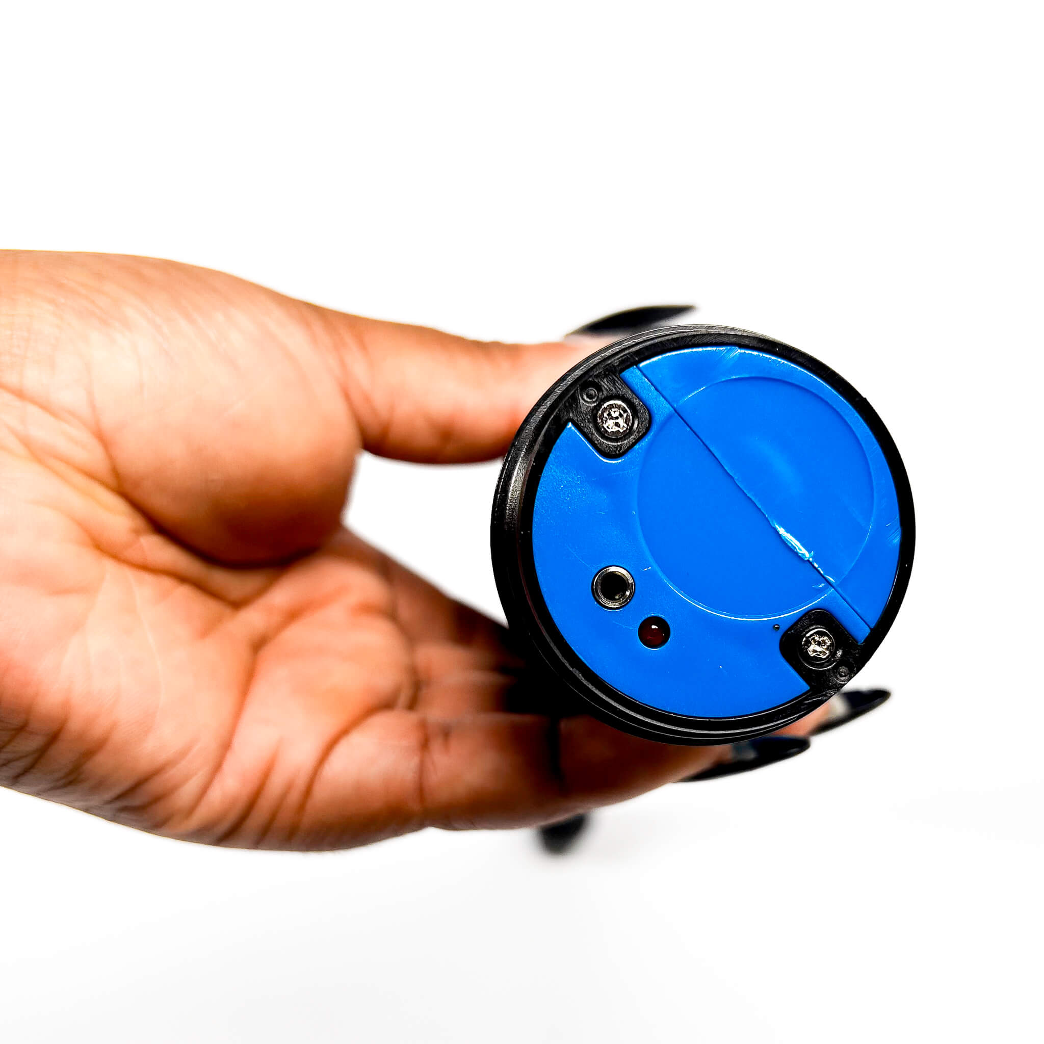 Hand holding a blue circular object with a black rim on a white background