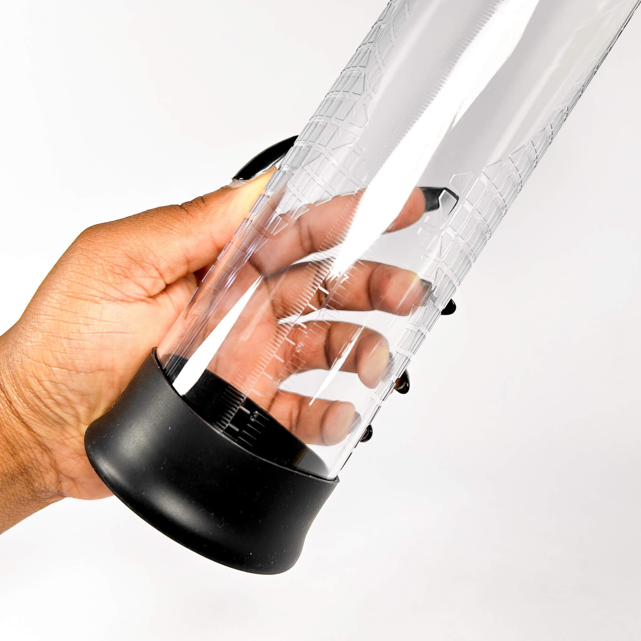 Hand holding a Power Up Pistol Penis Pump with a black base on a white background
