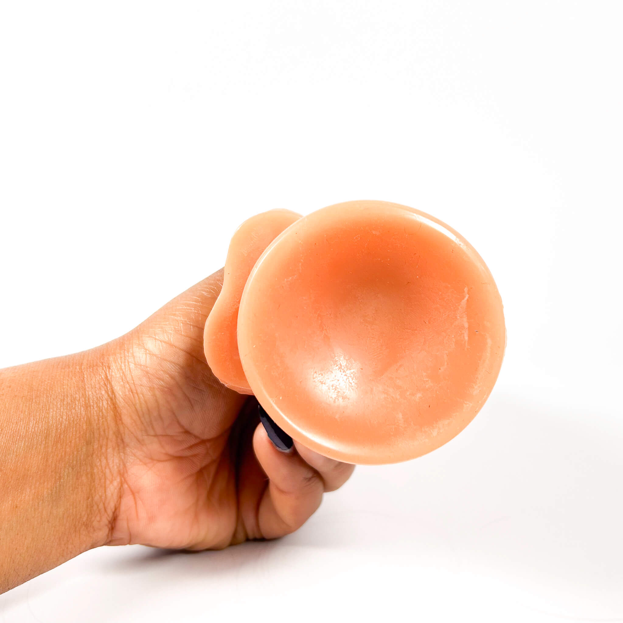 Hand holding a dildo against a white background
