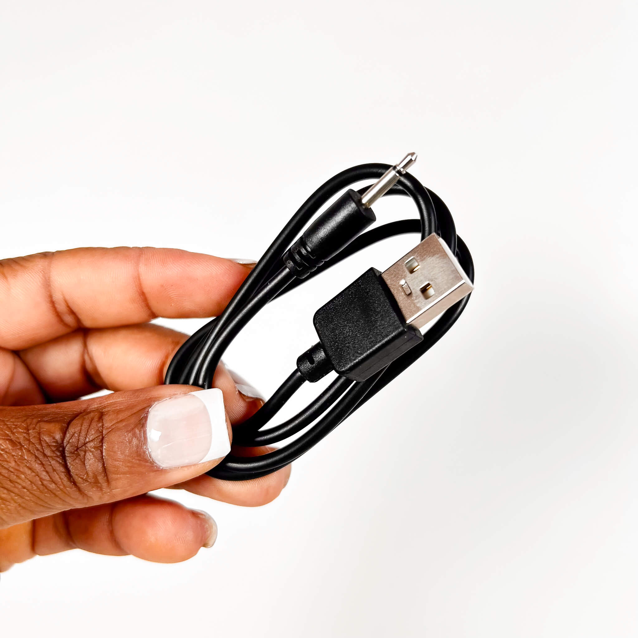 Hand holding a black USB cable with a white background