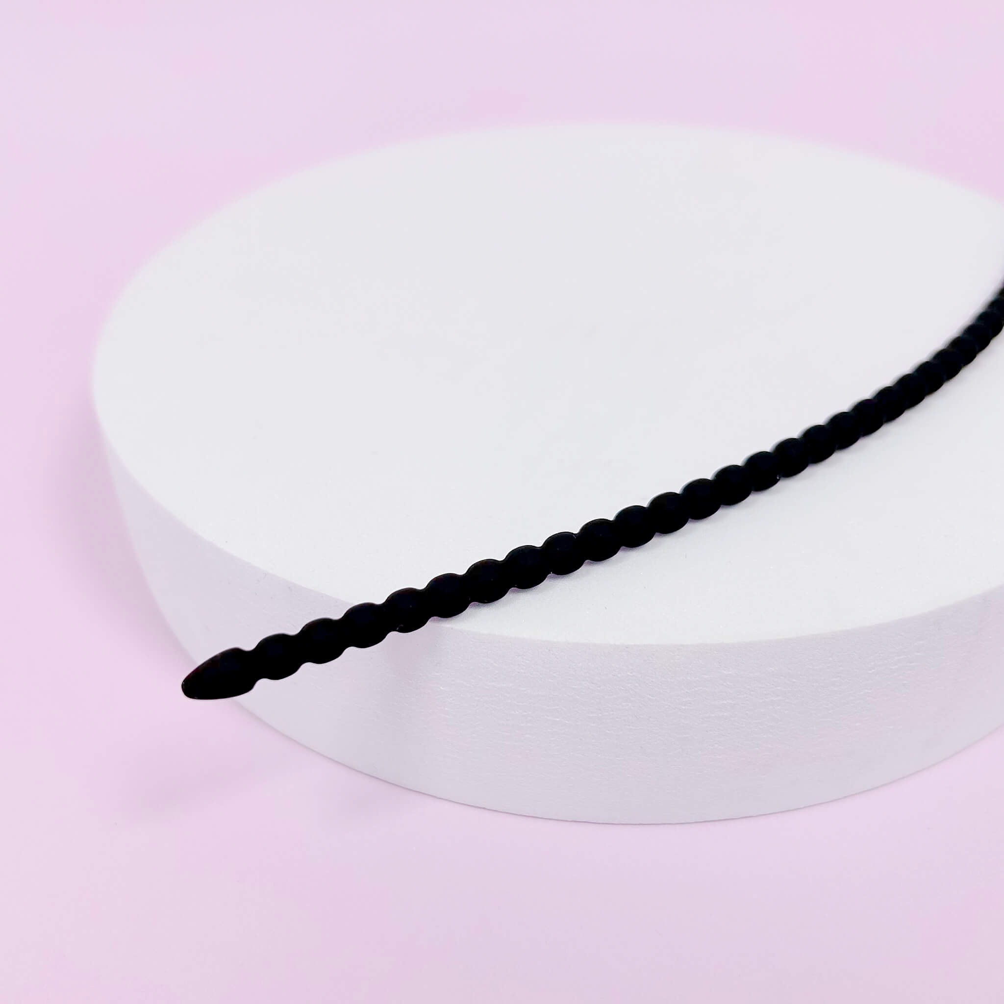 Small Silicone Urethral Plug on a white circular stand against a pink background