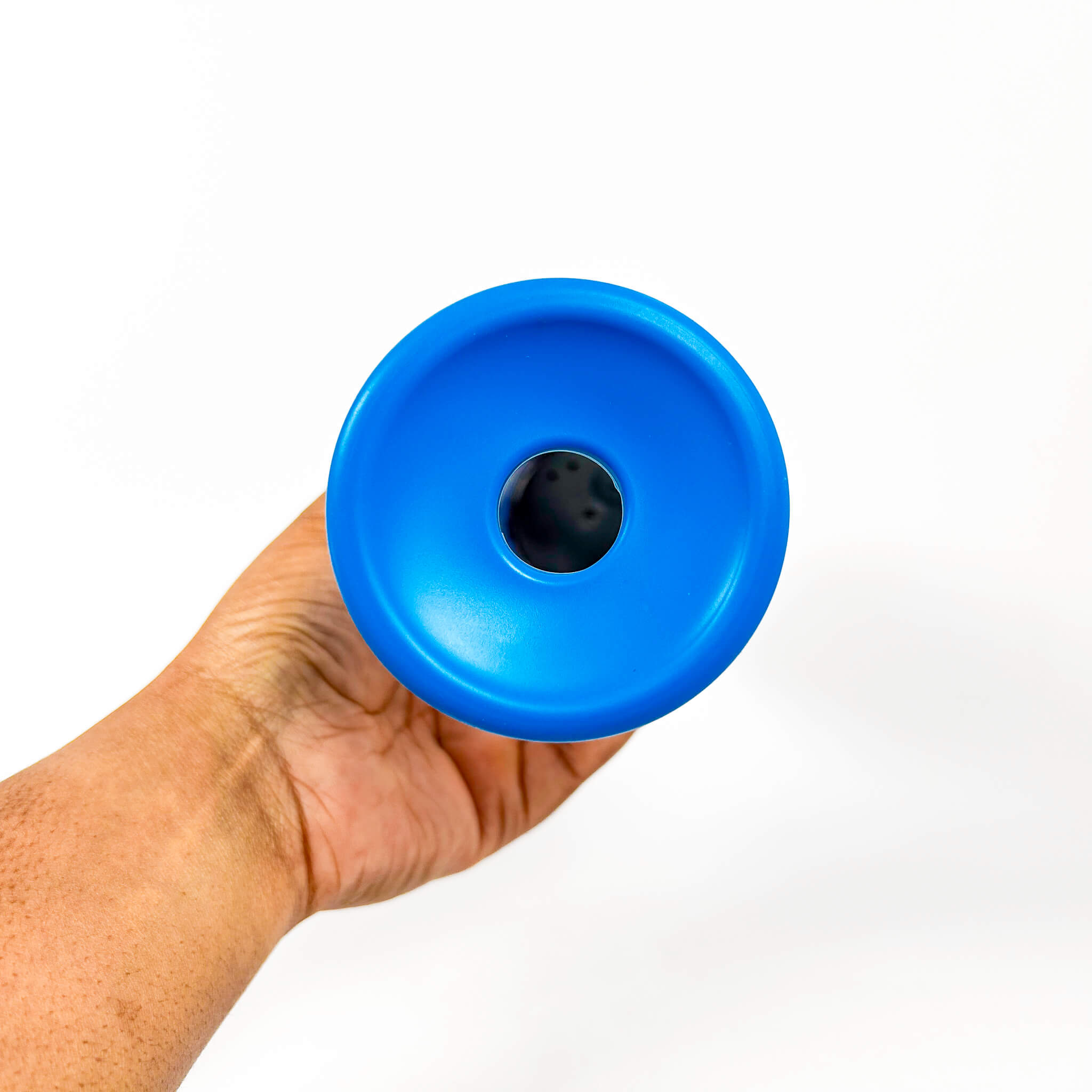 Hand holding a blue plastic cup with a black center on a white background