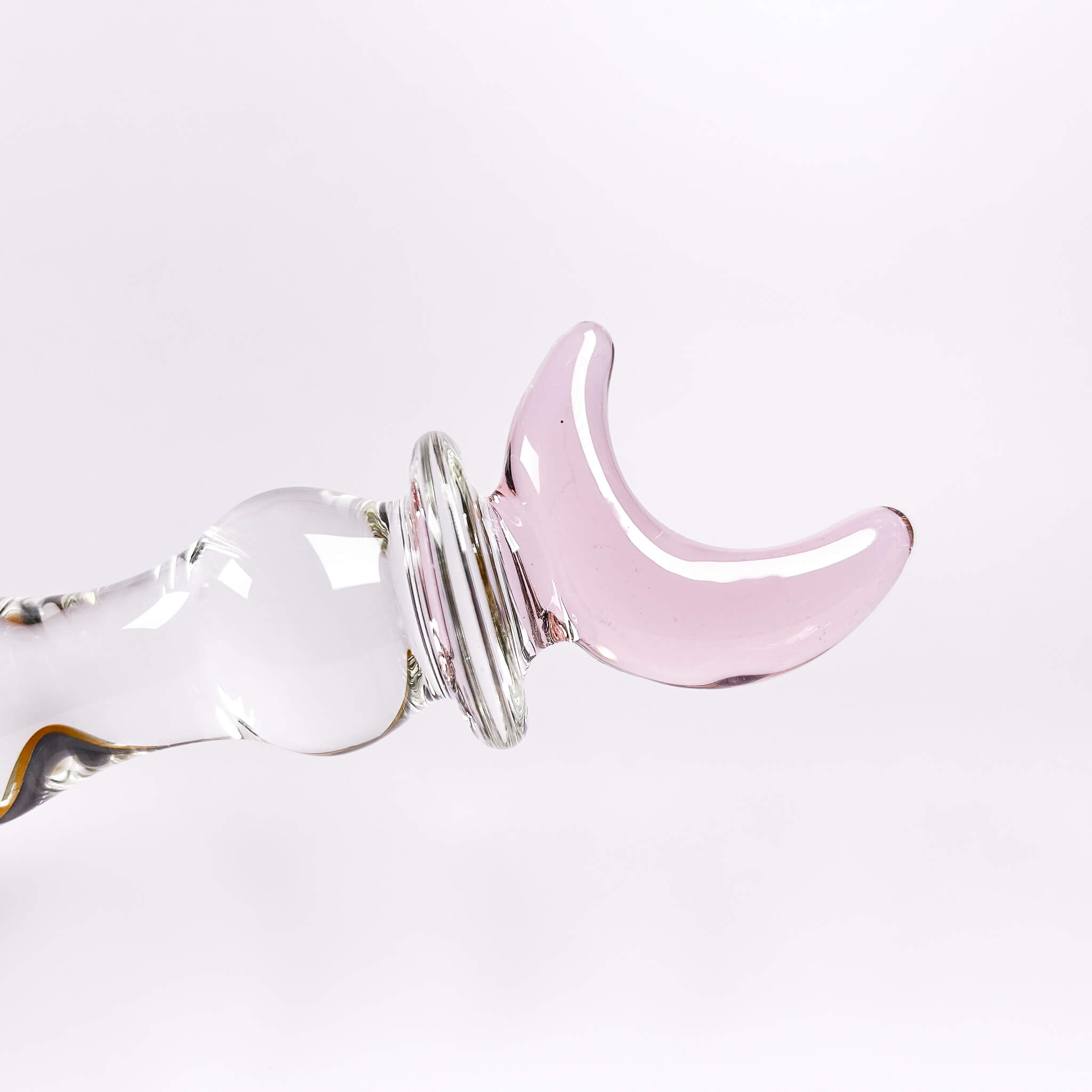 Pink crescent moon-shaped glass dildo on a white background