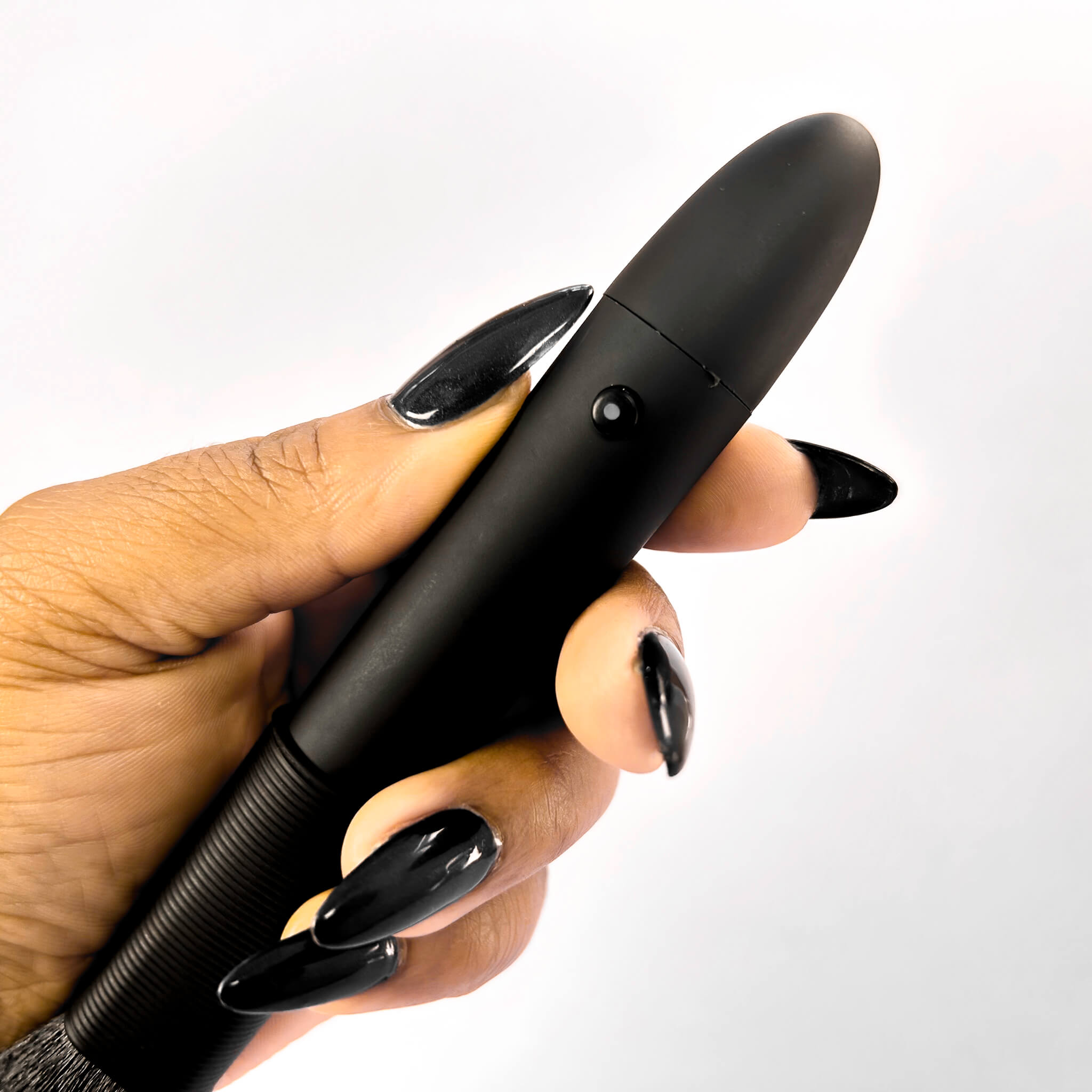 Hand holding a black brush vibratoragainst a white background