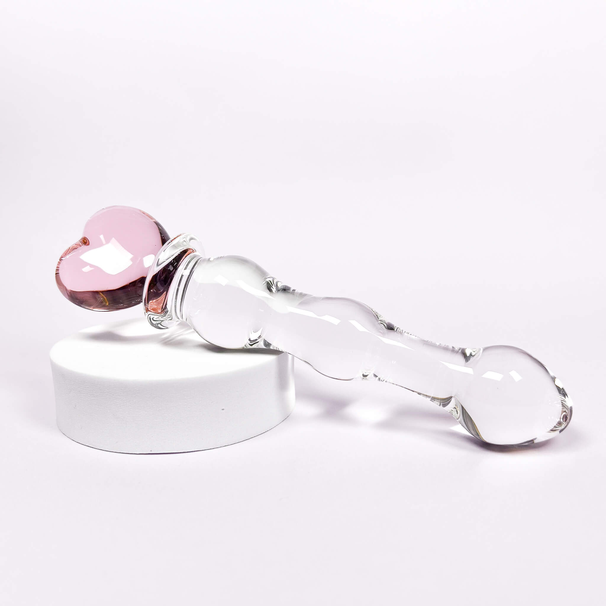 Glass dildo with pink heart-shaped piece on a white background