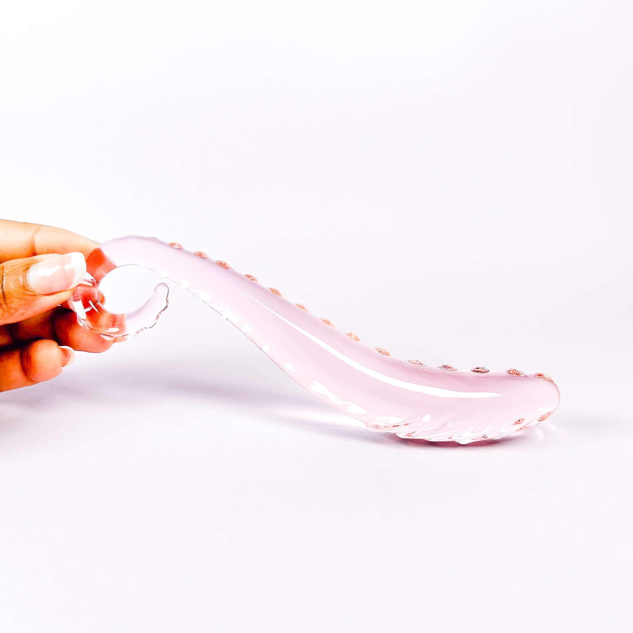 Pink glass dildos held by a hand on a white background