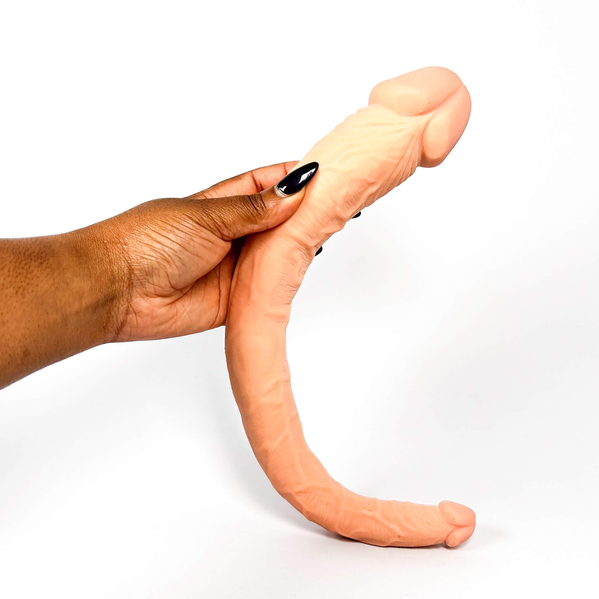 Hand holding a double ended dildo against a white background