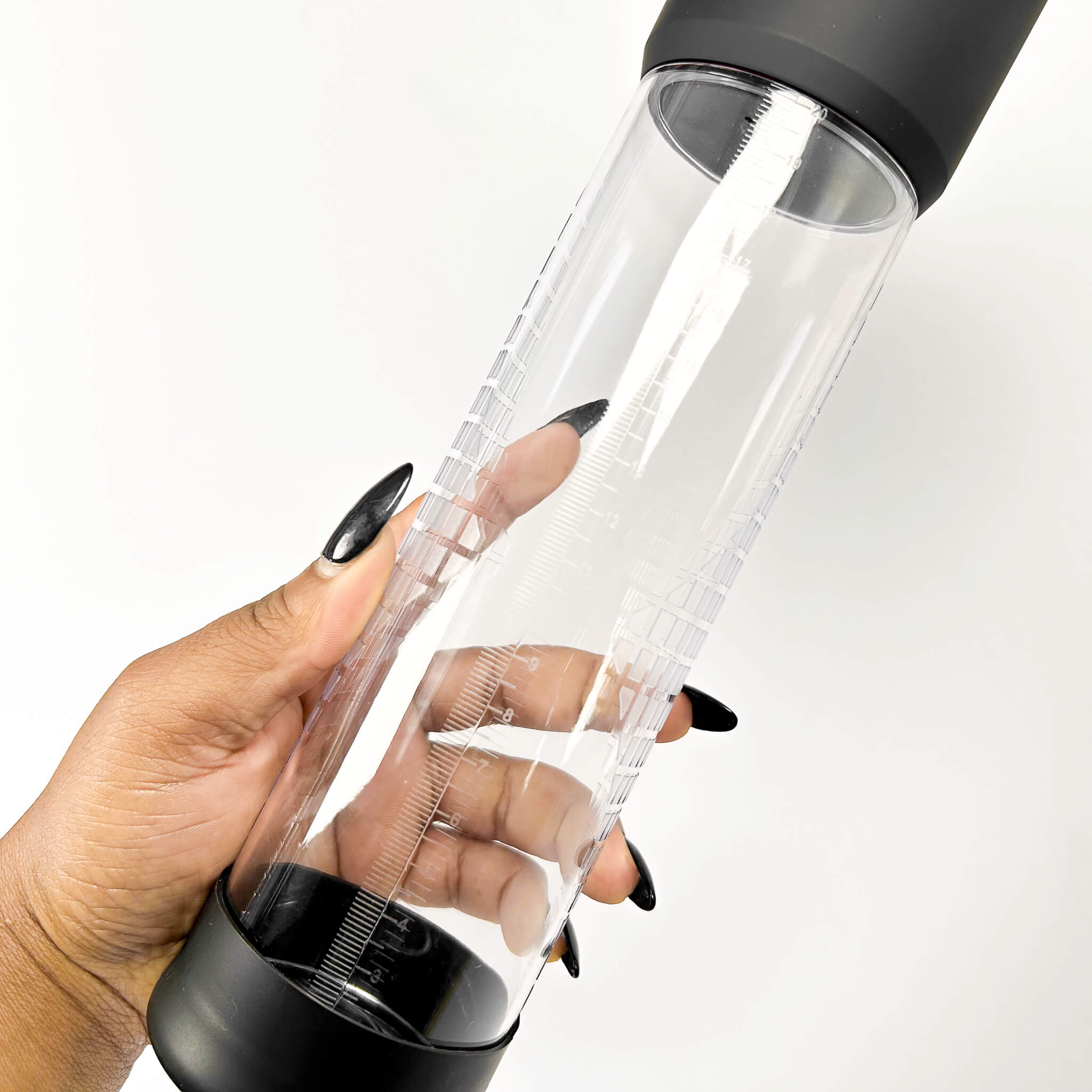 electric penis pump with black lid held by a hand on a white background