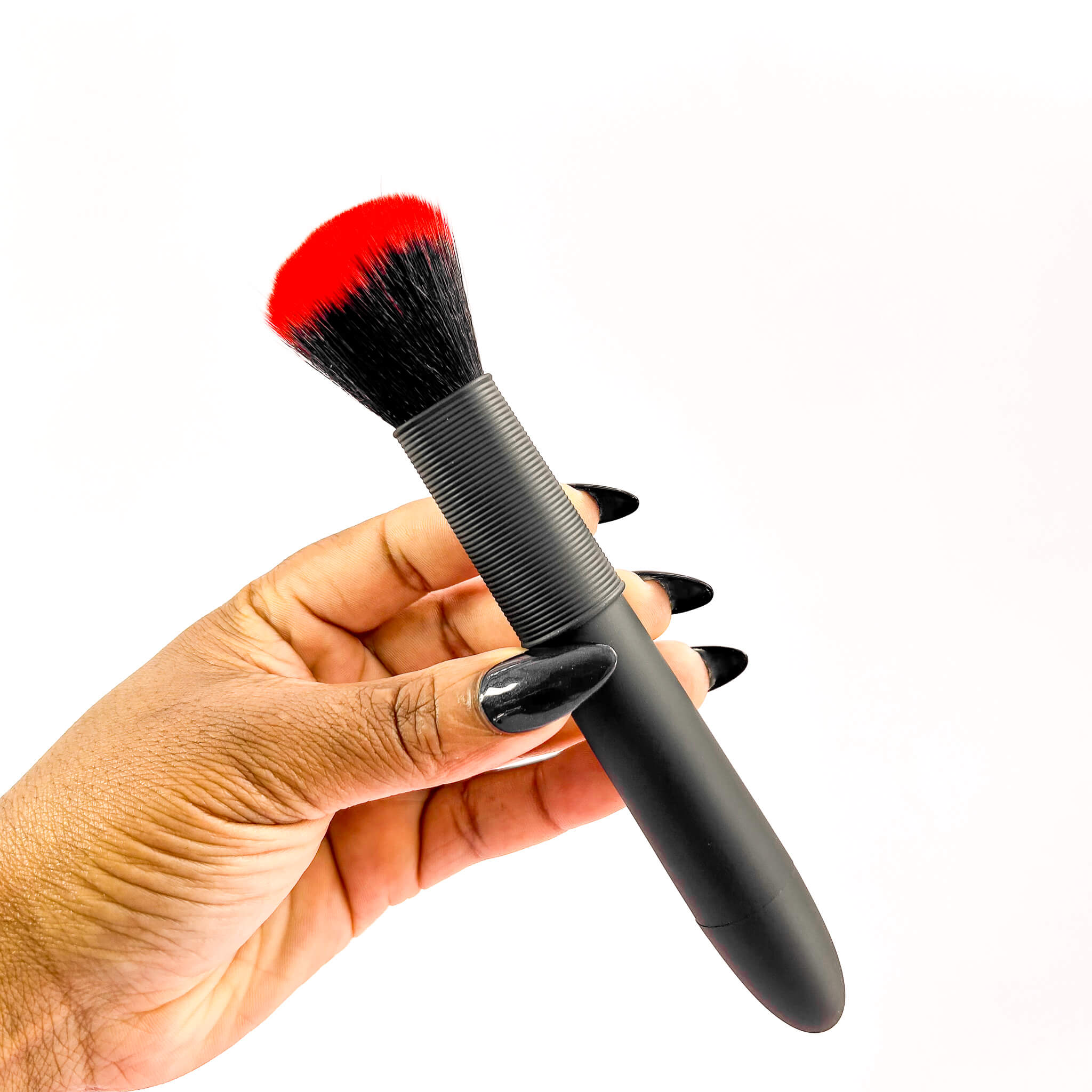 makeup brush vibrator with red bristle tip held by a hand on a white background