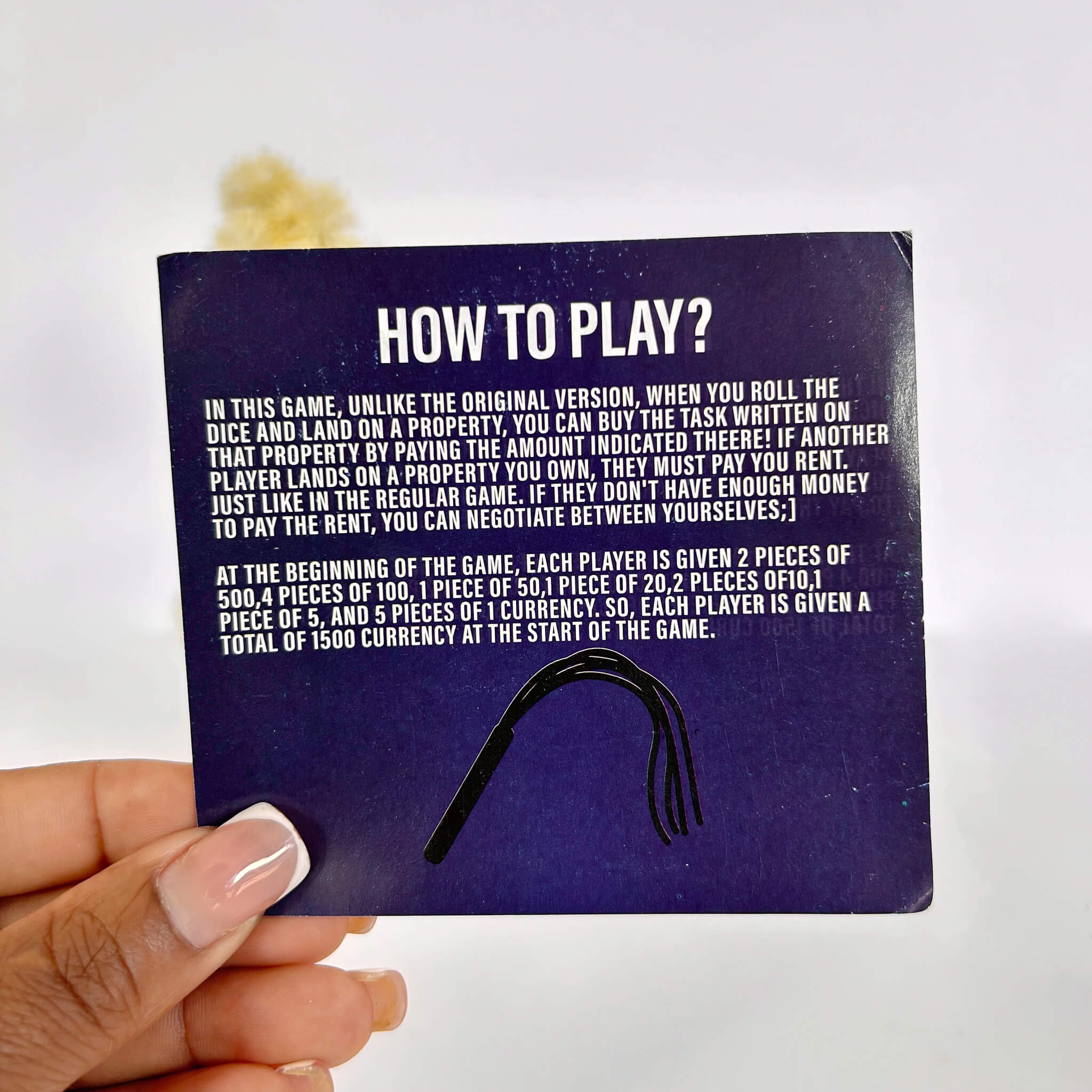 Hand holding a card with 'How to Play?' instructions on a white background
