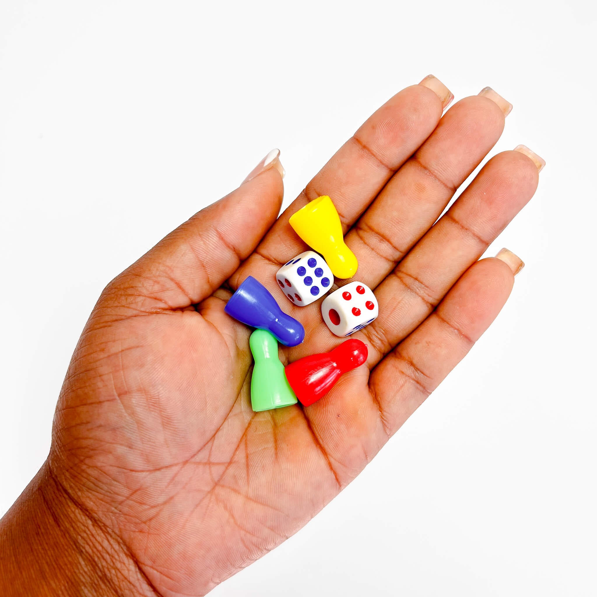 Hand holding colorful dice and game pieces against a white background