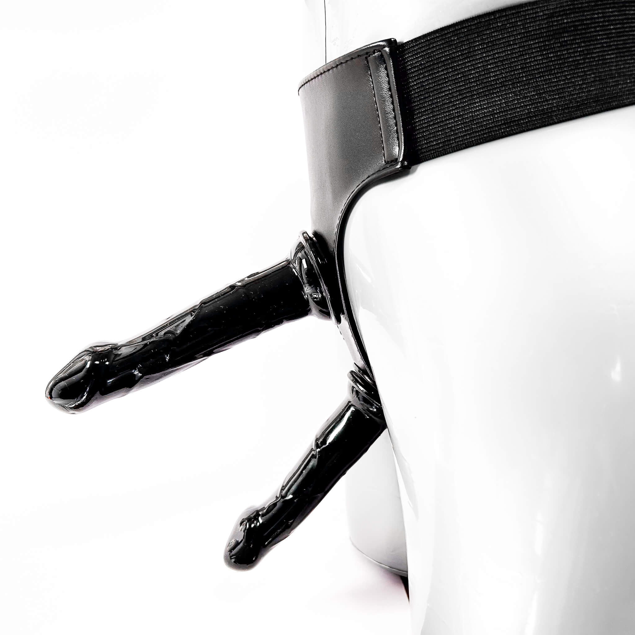 Black leather harness with a dildo on a white background