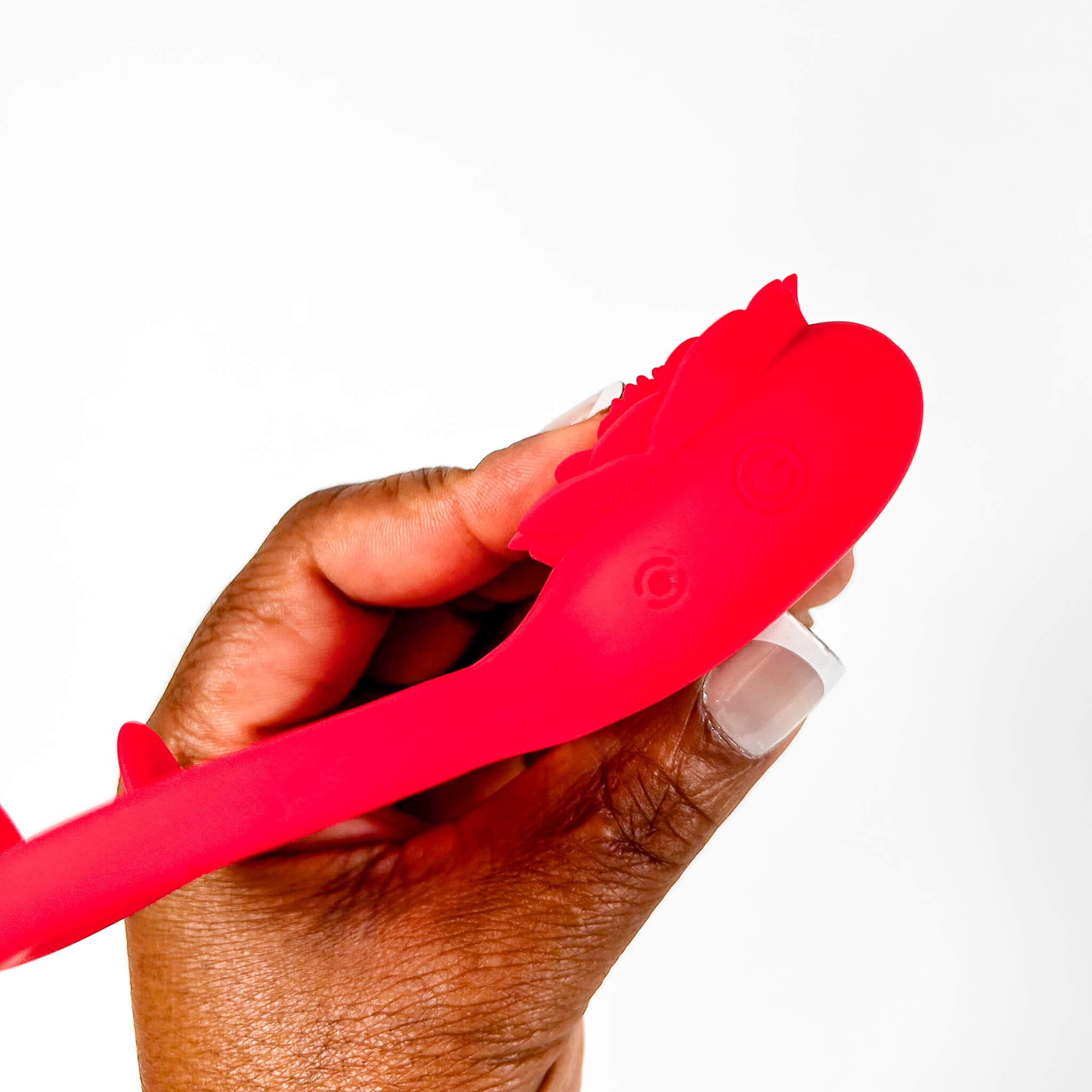 Hand holding a red rose cock ring tool with a white background