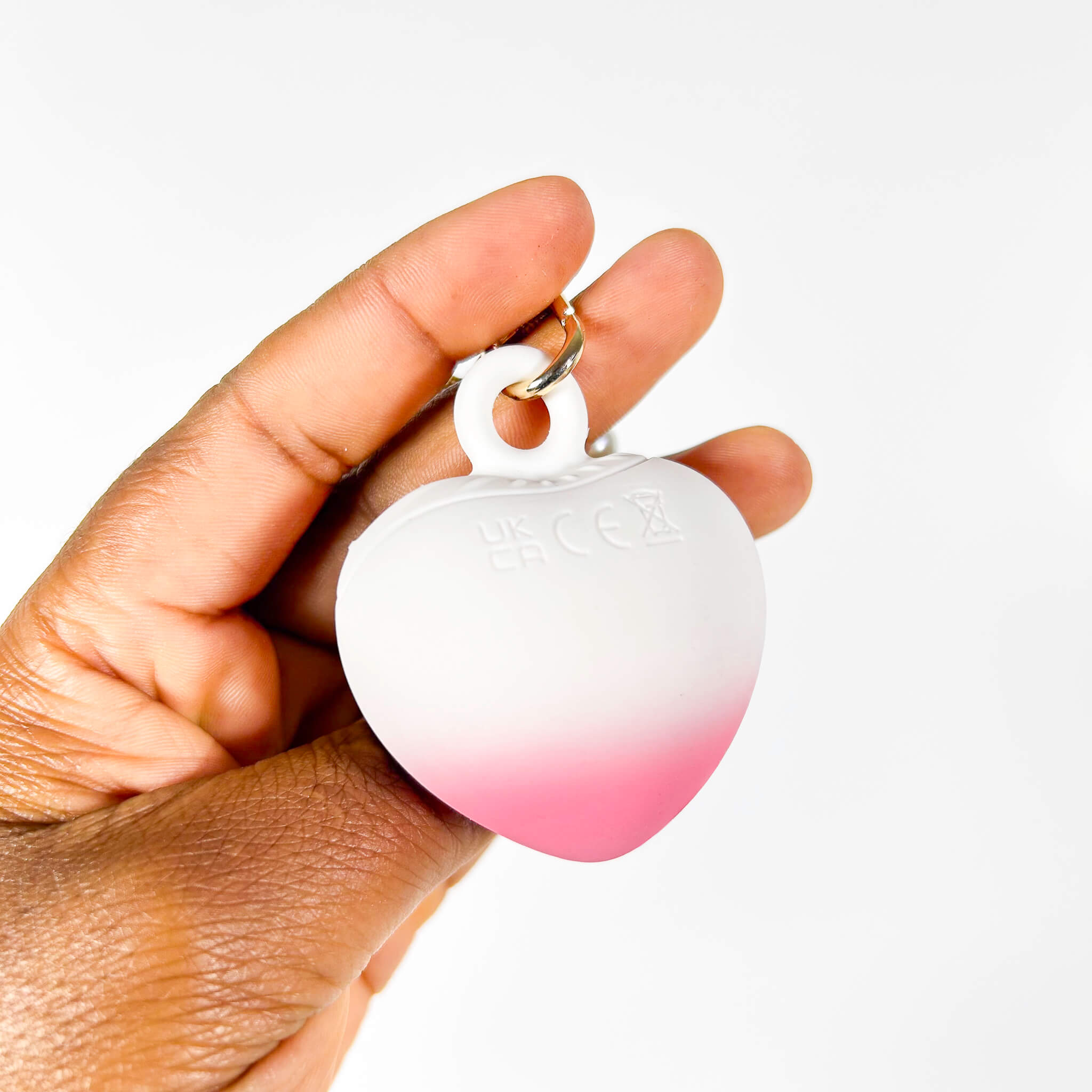 Hand holding a gradient pink to white small discreet vibrator for women on a white background