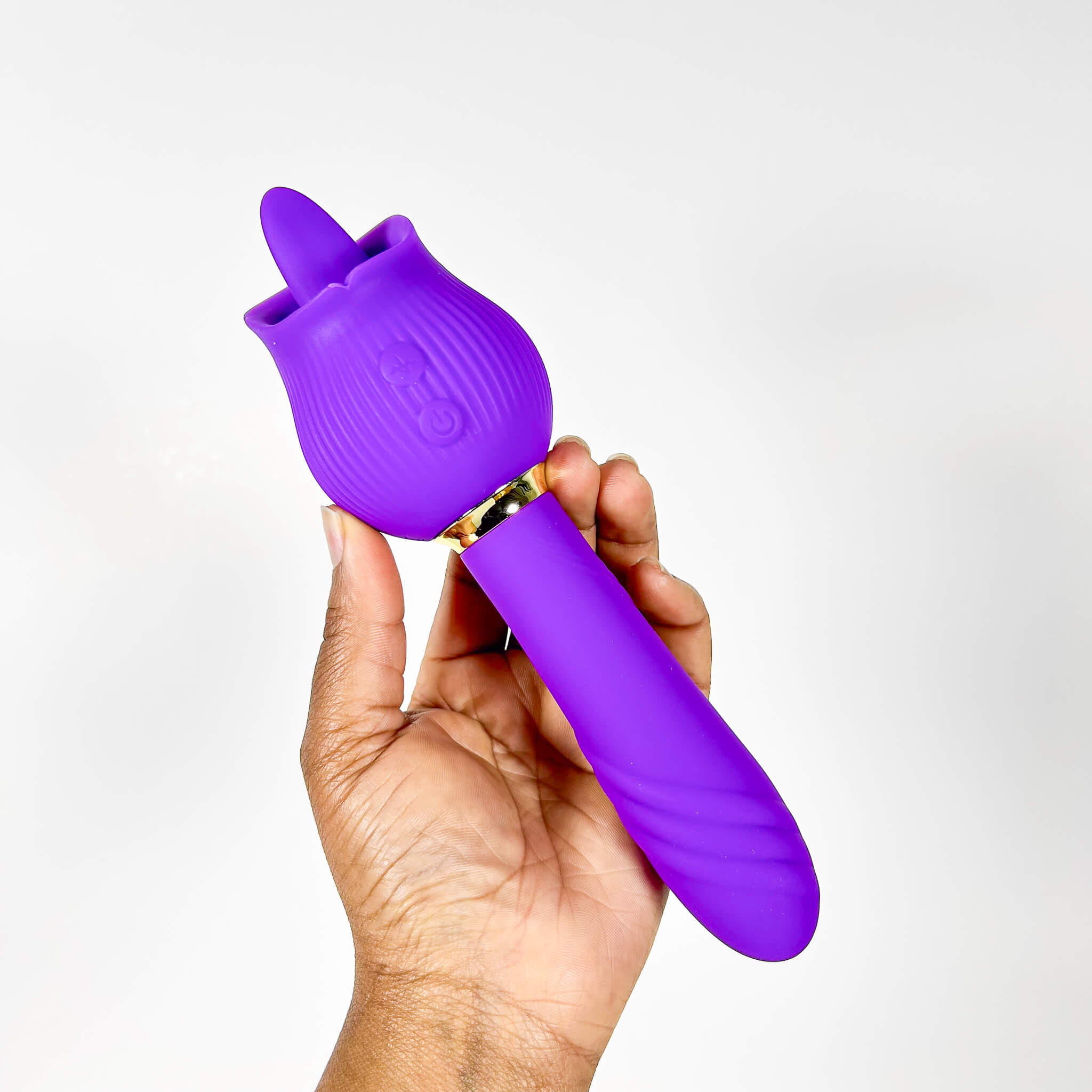 Purple tongue sex toy held in a hand against a white background