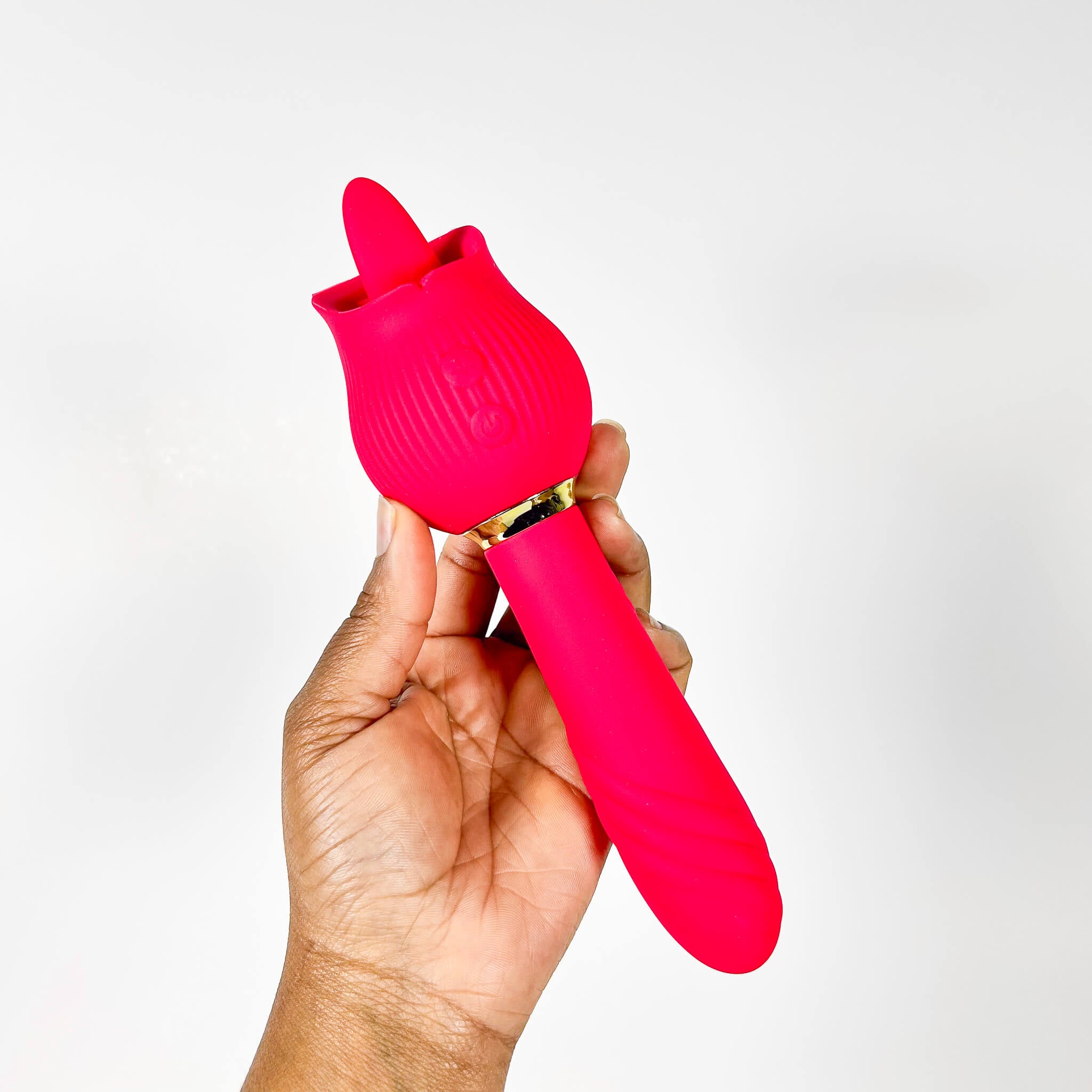 Hand holding a red silicone tongue sex toy against a white background