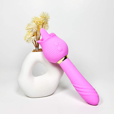Pink silicone 2 in 1 tongue vibrator with a white vase and yellow flowers on a light gray background
