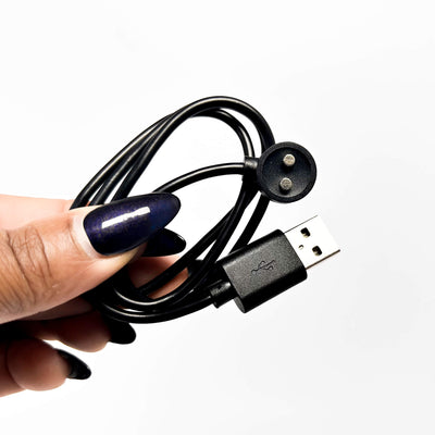 Hand holding a black USB cable with a plug on a white background