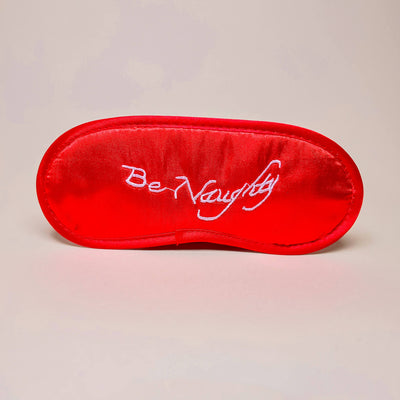 Red bedroom mask with 'Be Naughty' text on a beige background