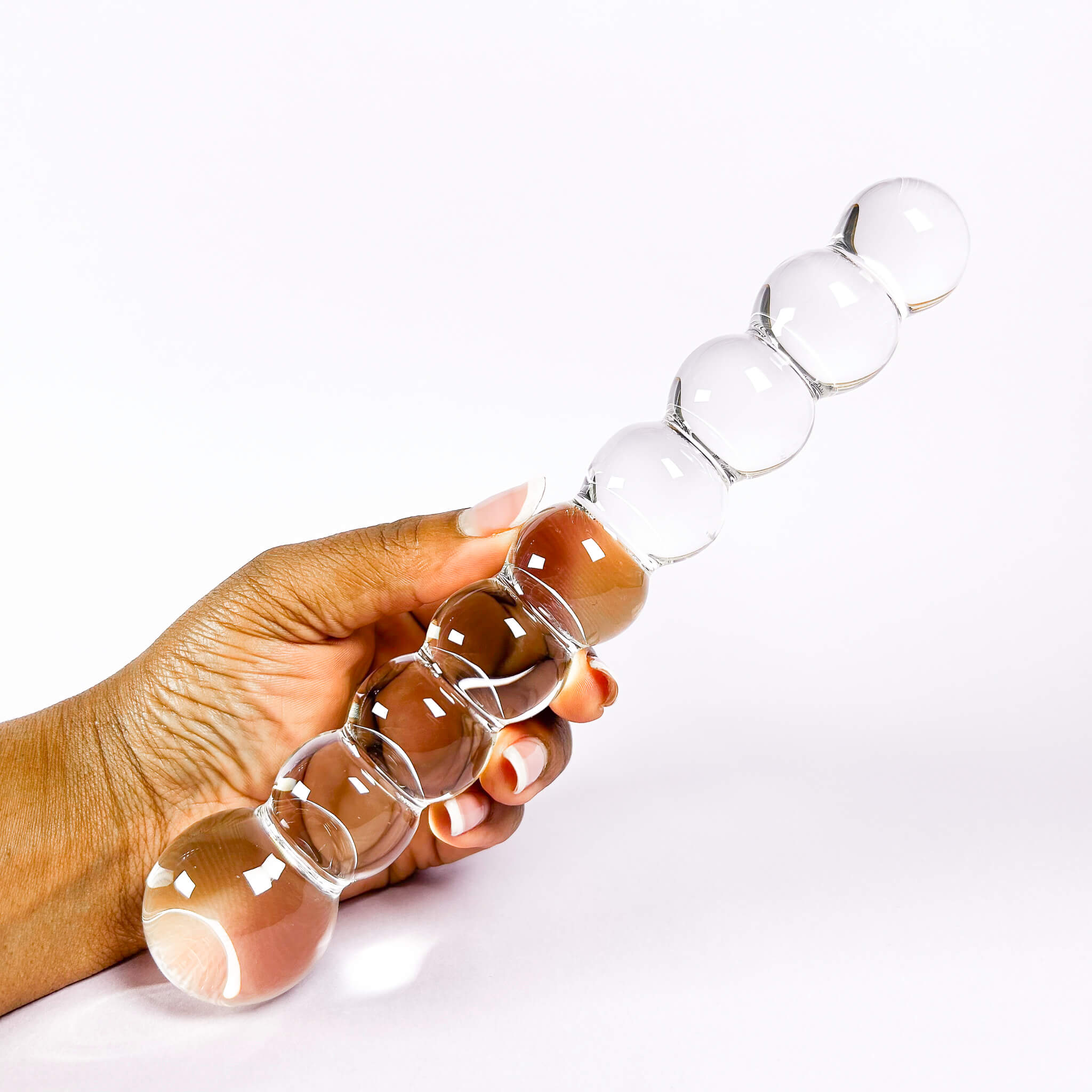 Hand holding a clear glass massager with beads on a white background