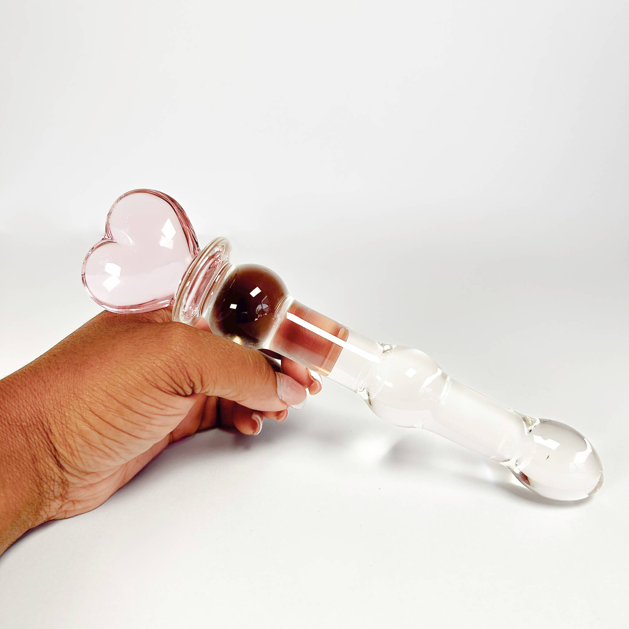 Hand holding a Beaded Sensual Glass Dildo on a white background