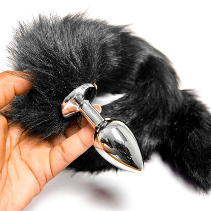 Black Extra Long Tail With Metal Butt Plug held by a hand on a white background