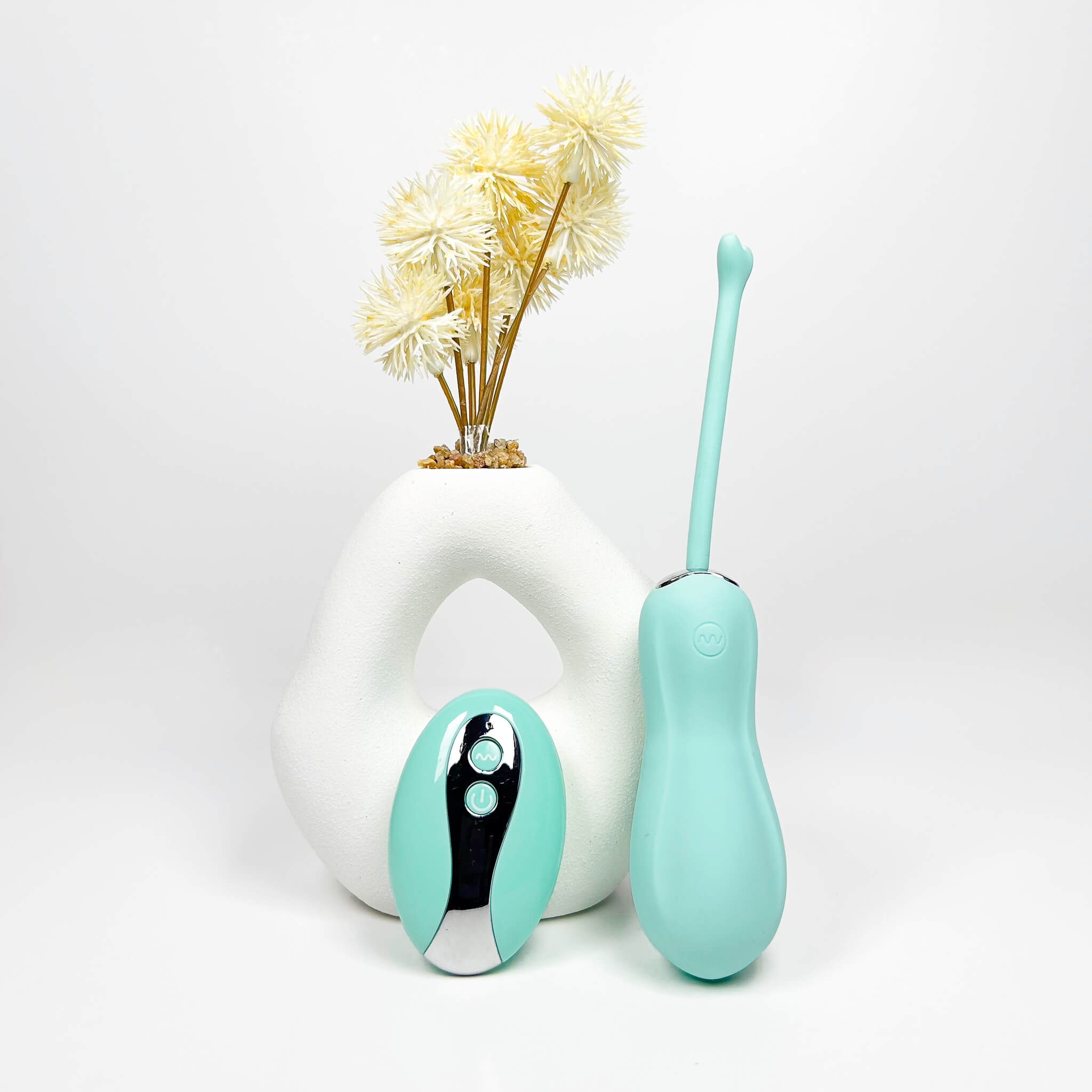 CurvePlay Insertable Remote Vibrator and white vase with yellow flowers on a light gray background