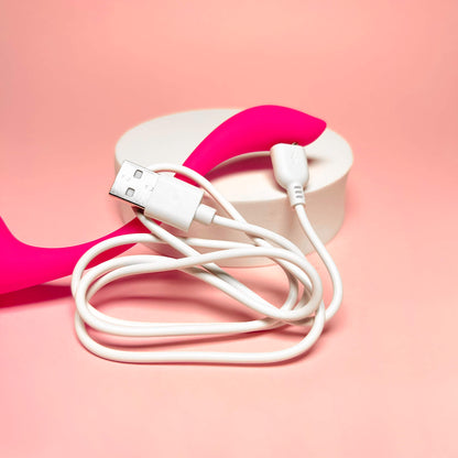 White USB cable with a pink and white heart-shaped object on a pink background