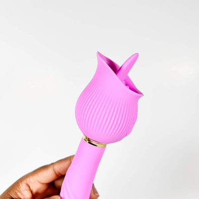Pink silicone Double Vibrator held by a hand against a white background