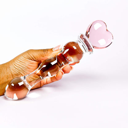 Fairy Wand Glass Dildo with Heart handle held by a hand on a white background