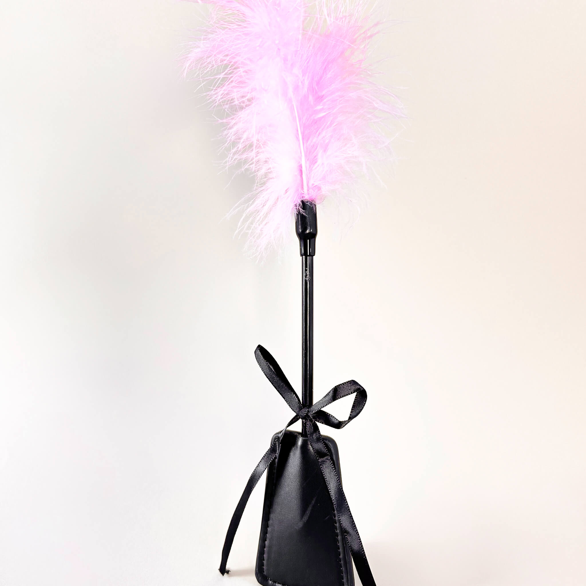 Black feather duster with pink feathers on a white background