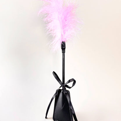 Black feather duster with pink feathers on a white background