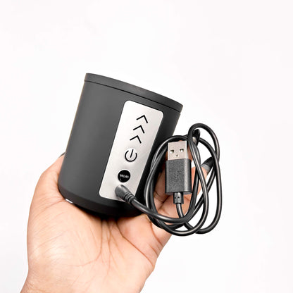 Black electronic device with USB cable held in a hand against a white background