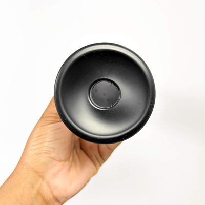 Black suction cup held in a hand against a white background