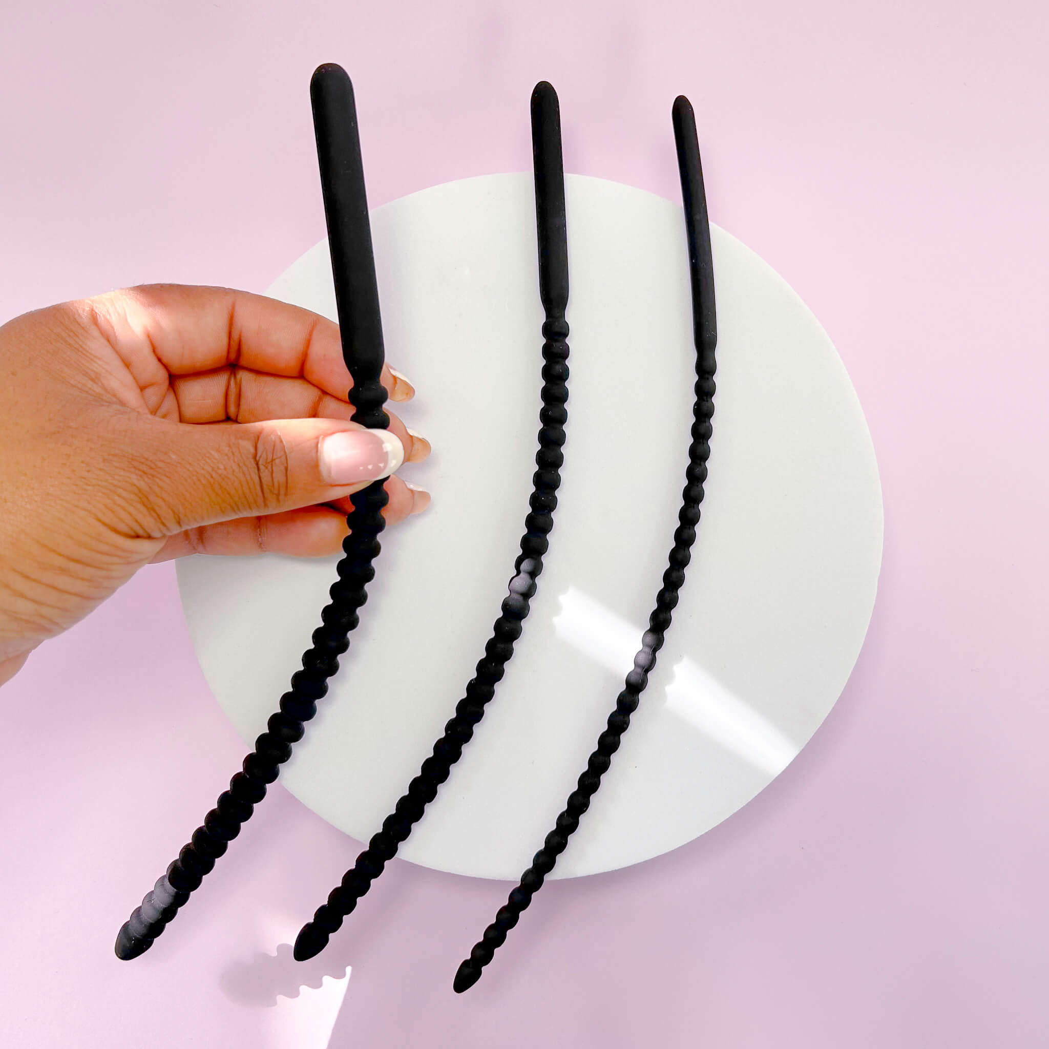 Flexible Ribbed Silicone Urethral Plug Set on a white plate against a pink background