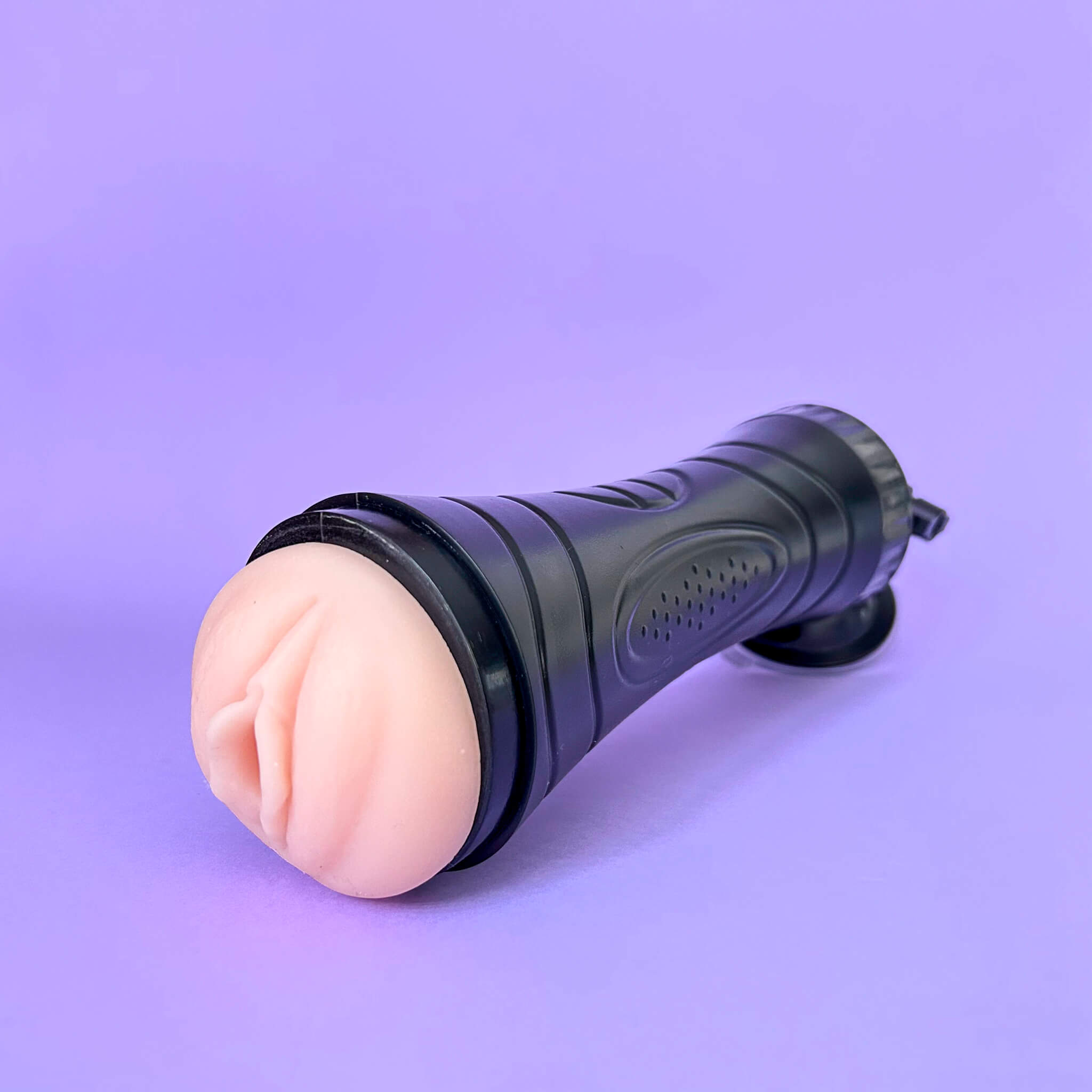 Black fleshlight with a pinkish-brown handle on a purple background