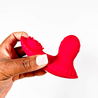 Red silicone Insertable Panty Vibrator with Remote held by a hand on a white background
