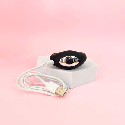 Black electronic device with a white cable on a pink background