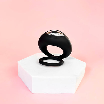 Black cock ring on a white platform with a pink background