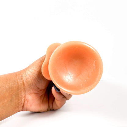 Hand holding a dildo against a white background