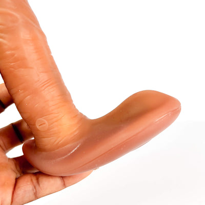 Hand holding a silicone product shaped like a finger on a white background