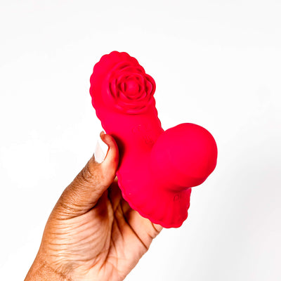 Red silicone Remote Insertable Panty Vibrator held by a hand on a white background