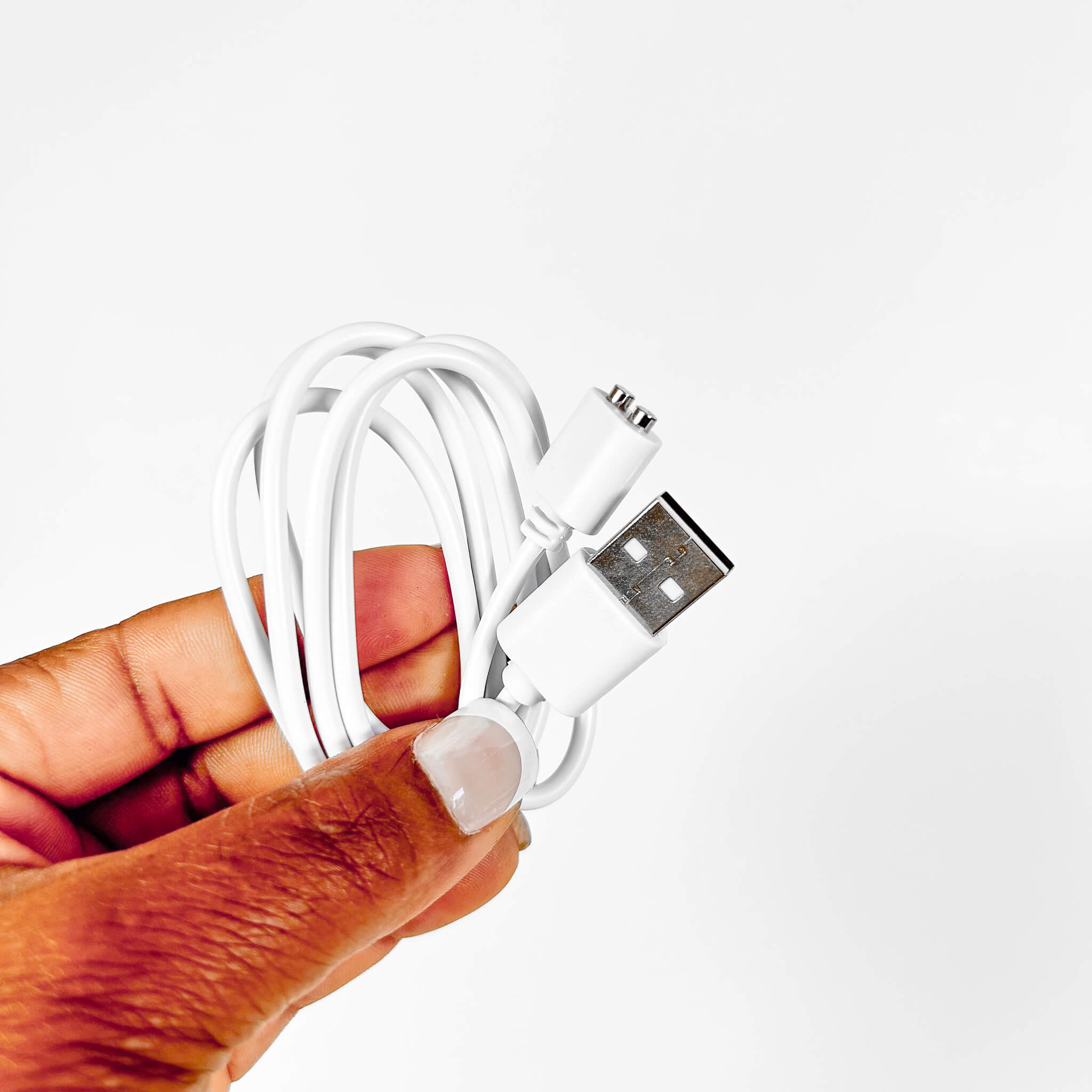 Hand holding a white USB cable with a metallic connector on a light gray background