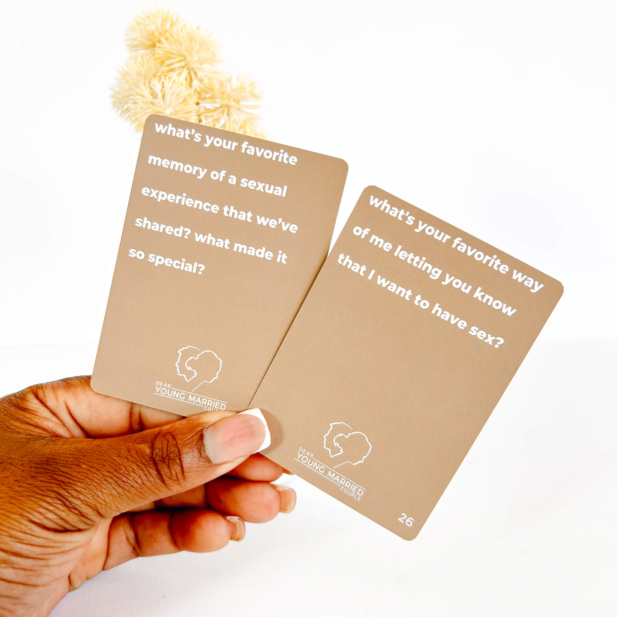 Two brown sexpectations cards with white text held by a hand